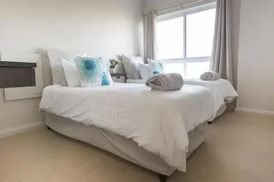 two white beds in a room with a window at 2 Bedroom apartment with Breathtaking Views! in Cape Town