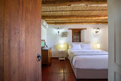a bedroom with a bed and a table in a room at Denneboom Vineyards and Wildlife in Paarl