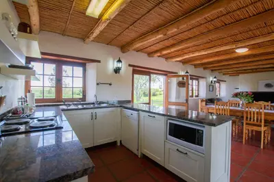 a large kitchen with white cabinets and a table at Denneboom Vineyards and Wildlife in Paarl