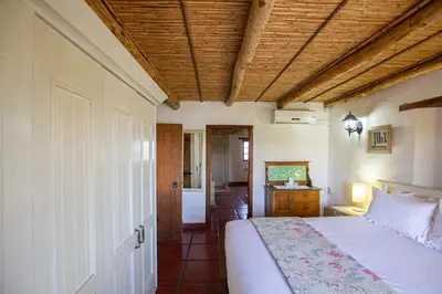 a bedroom with a white bed with a wooden ceiling at Denneboom Vineyards and Wildlife in Paarl
