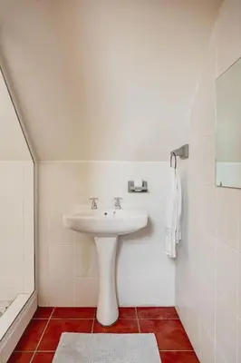 a bathroom with a white sink and red tiles at Le Arc Manor House in Franschhoek