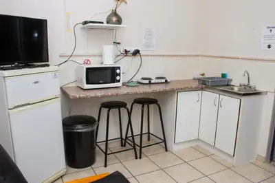 a kitchen with a counter with a microwave and stools at Helderzicht Self-Catering in Brackenfell