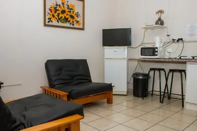 a living room with a chair and a microwave at Helderzicht Self-Catering in Brackenfell