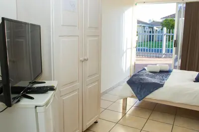 a bedroom with a bed and a tv and a desk at Helderzicht Self-Catering in Brackenfell