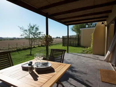 a wooden table with wine glasses on a patio at Wild Clover Cottages in Stellenbosch