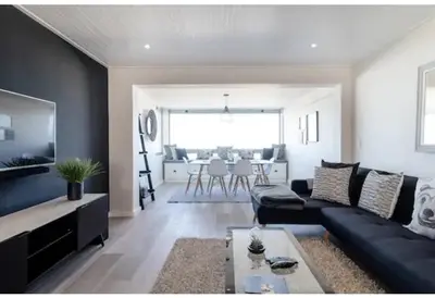 a living room with a black couch and a table at 67 Whale Rock Estate, Hermanus in Hermanus