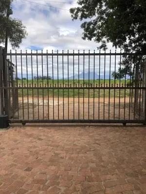 a black fence with a view of a field behind it at The Vineyard East in Joostenberg Vlakte