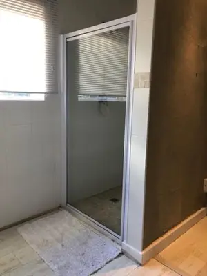 a glass shower door in a room with a window at The Vineyard East in Joostenberg Vlakte