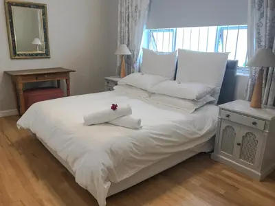 a bedroom with a white bed with a flower on it at Protea Suite in Cape Town