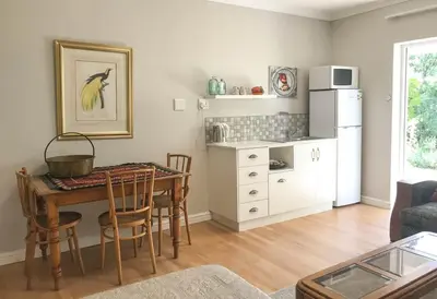 a living room with a table and a kitchen at Protea Suite in Cape Town