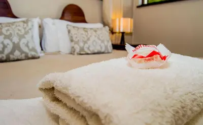 a white blanket on a bed with a bag on it at Ladera - Vista Self-catering Guesthouse in Paarl
