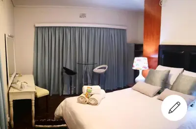 a bedroom with a large white bed and a lamp at The Room in Cape Town