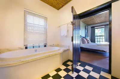 a bathroom with a bath tub and a bedroom at Bartinney Private Cellar Banhoek in Stellenbosch