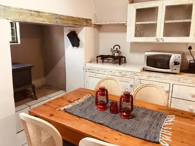 a kitchen with a wooden table with chairs and a microwave at Kleine Vrede Farm Cottage in Hermanus