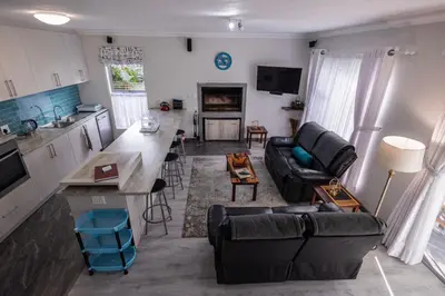 a living room with a black couch and a kitchen at Bem Vindo Self Catering Guest House in Hermanus