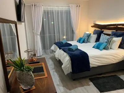 a bedroom with a large bed with blue pillows at Bem Vindo Self Catering Guest House in Hermanus