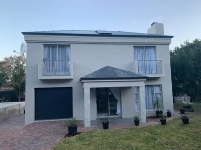 a white house with a large garage at Bem Vindo Self Catering Guest House in Hermanus