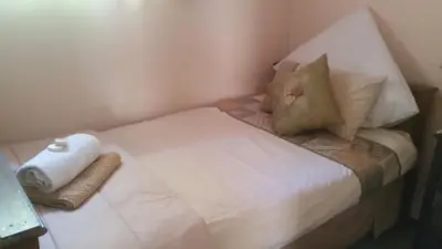 a small bed with white sheets and pillows on it at Alpaca Self Catering Cottage Kleinmond in Kleinmond