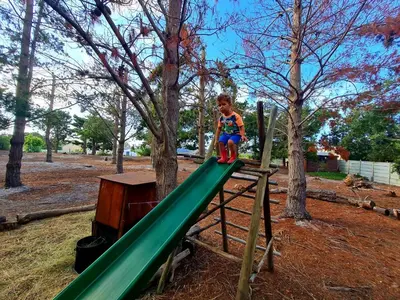 a young boy sitting on a slide at a playground at Alpaca Self Catering Cottage Kleinmond in Kleinmond