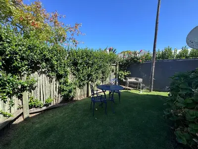 a patio with a table and chairs in a yard at Jasmine Cottage - Fast Wi-Fi, slow living in Hermanus