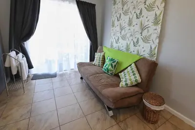 a living room with a brown couch with green pillows at Caesar's Self-catering Open Plan Suite in Somerset West