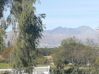 a tree with a white fence and mountains in the background at Caesar's Self-catering Open Plan Suite in Somerset West