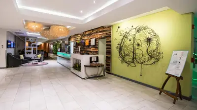 a lobby with a green wall with a drawing on it at Hotel Verde Cape Town Airport in Matroosfontein