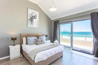a bedroom with a bed with a view of the ocean at Sea Spray B403 by CTHA in Bloubergstrand