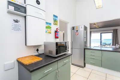 a kitchen with a counter with a microwave and a refrigerator at Sea Spray B403 by CTHA in Bloubergstrand