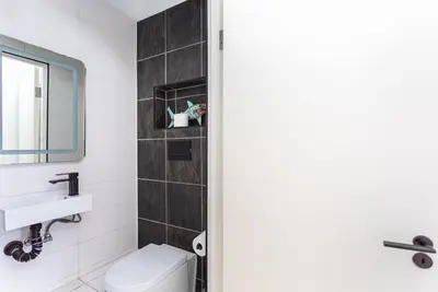 a bathroom with a white toilet and a sink at Sea Spray B403 by CTHA in Bloubergstrand