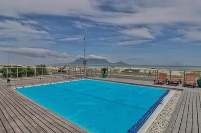 a swimming pool on a deck with a view of the beach at Sea Spray B403 by CTHA in Bloubergstrand