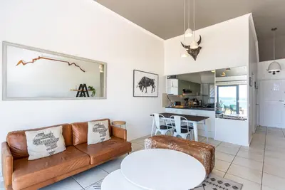 a living room with a couch and a table at Sea Spray B403 by CTHA in Bloubergstrand