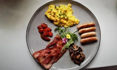 a plate of breakfast food with sausage and eggs at Kianga in Gordonʼs Bay