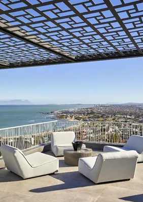 a patio with chairs and a view of the ocean at Kianga in Gordonʼs Bay