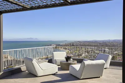 a balcony with chairs and a view of the ocean at Kianga in Gordonʼs Bay