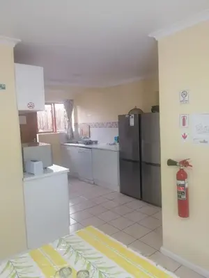 a kitchen with white cabinets and a refrigerator at Pelican Accommodation Ottery in Cape Town