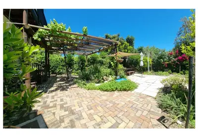 a garden with a pergola and a brick patio at Studio on McLeod - Private Self-catering Apartment in Somerset West