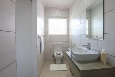 a white bathroom with a sink and a toilet at Milo's Sky Grey Guest House - No Load shedding in Cape Town