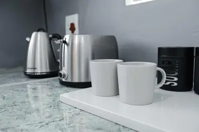 two white cups sitting on a counter in a kitchen at Milo's Sky Grey Guest House - No Load shedding in Cape Town