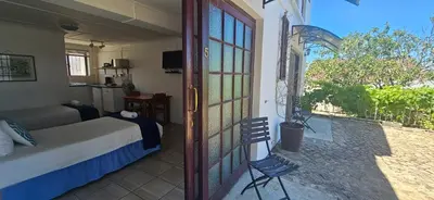 a bedroom with a bed and a sliding glass door at Kelkiewyn Guesthouse Caledon in Caledon