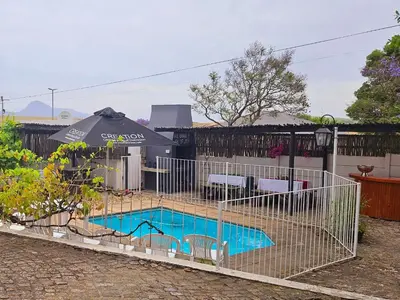a metal fence around a swimming pool with an umbrella at Kelkiewyn Guesthouse Caledon in Caledon