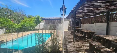 a swimming pool with a table and benches next to a fence at Kelkiewyn Guesthouse Caledon in Caledon