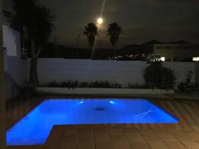 a blue swimming pool in a backyard at night at B&B Sauvignon Country Lodge in Wellington