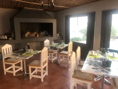 a dining room with a table and chairs and a fireplace at B&B Sauvignon Country Lodge in Wellington