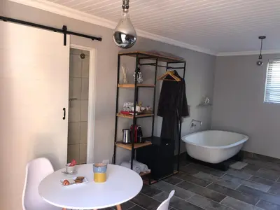 a bathroom with a tub and a white table and a bath tub at B&B Sauvignon Country Lodge in Wellington