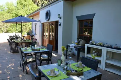 a patio with tables and chairs and an umbrella at B&B Sauvignon Country Lodge in Wellington