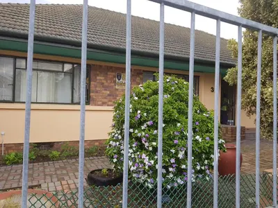a fence in front of a house with flowers at Canterbury Self-catering in Bellville