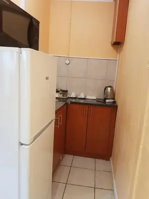 a small kitchen with a white refrigerator and brown cabinets at Canterbury Self-catering in Bellville
