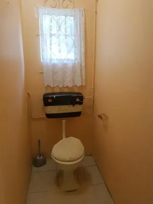a small bathroom with a toilet and a window at Canterbury Self-catering in Bellville