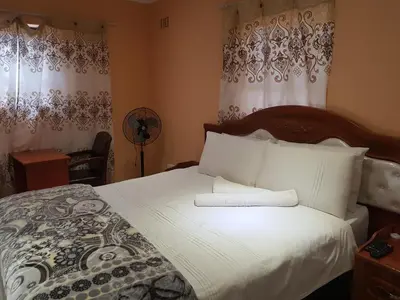 a bedroom with a large bed with white sheets at Canterbury Self-catering in Bellville